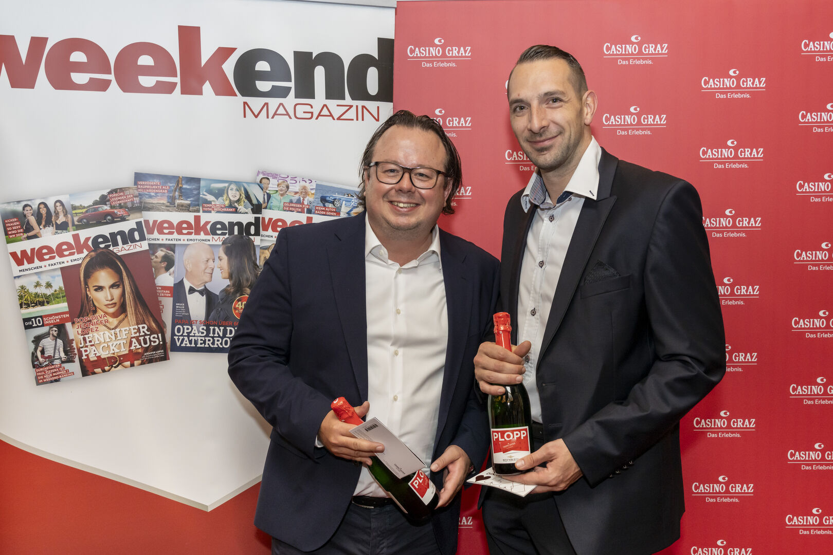 Zwei Männer in Anzügen lächeln in die Kamera