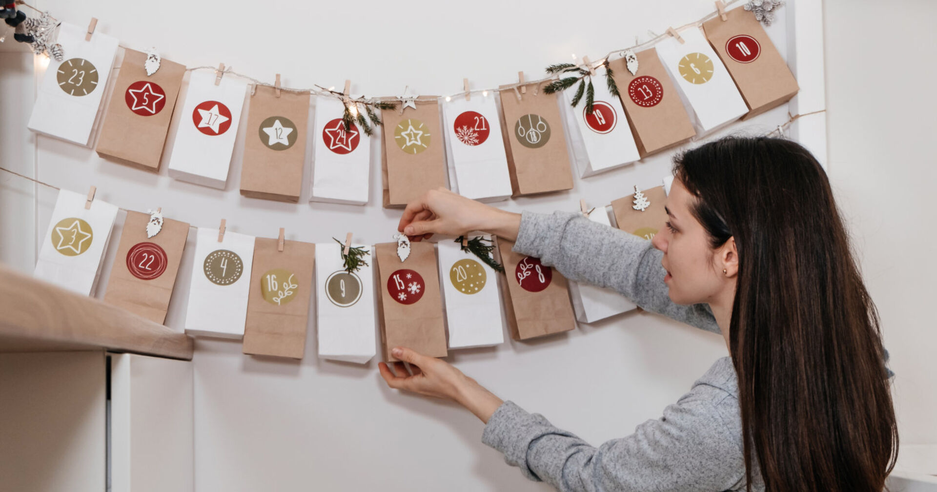 Frau hängt einen selbstgemachten Adventkalender an die Wand