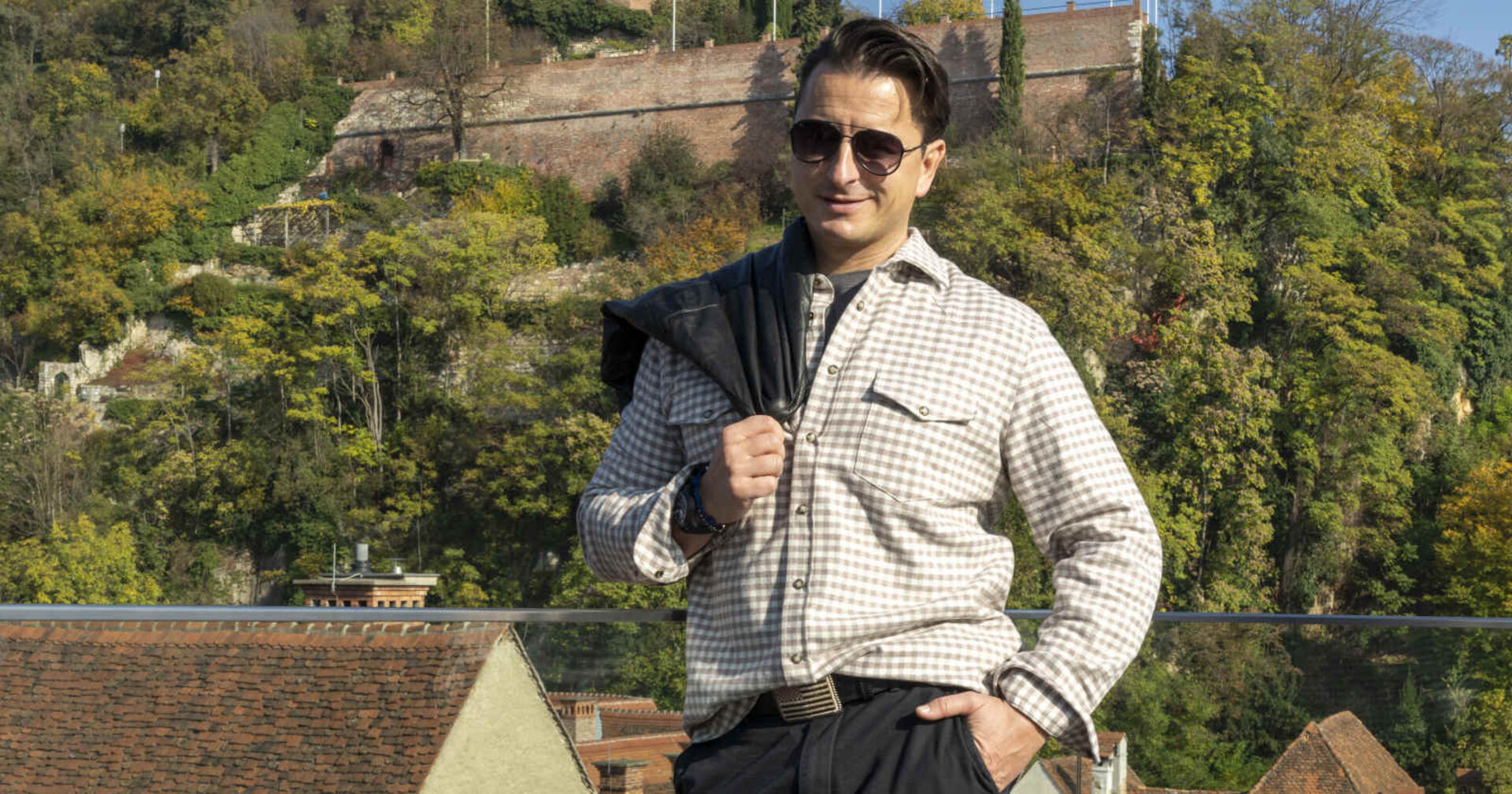 Mann posiert für die Kamera, seine Jacke hat er über seine Schulter gehängt