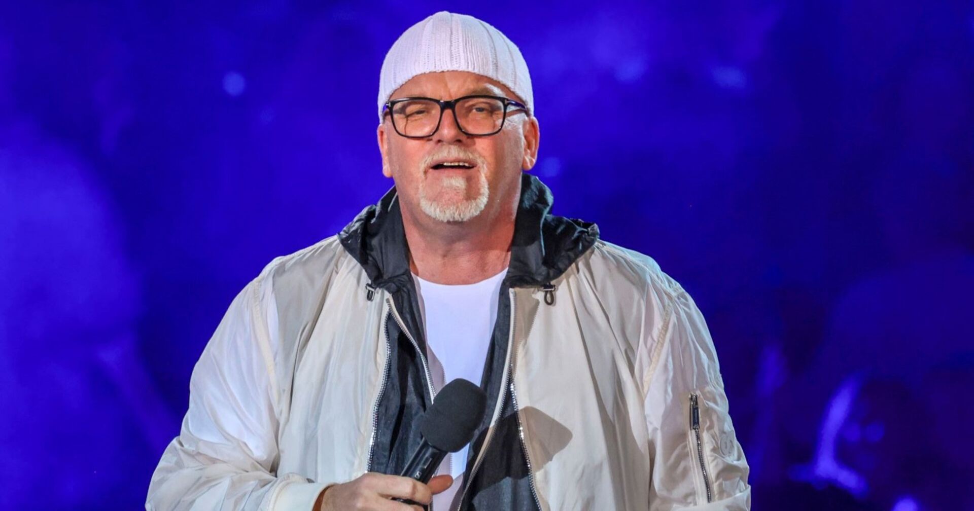 DJ Özi steht auf der Bühne mit Mikro in der Hand