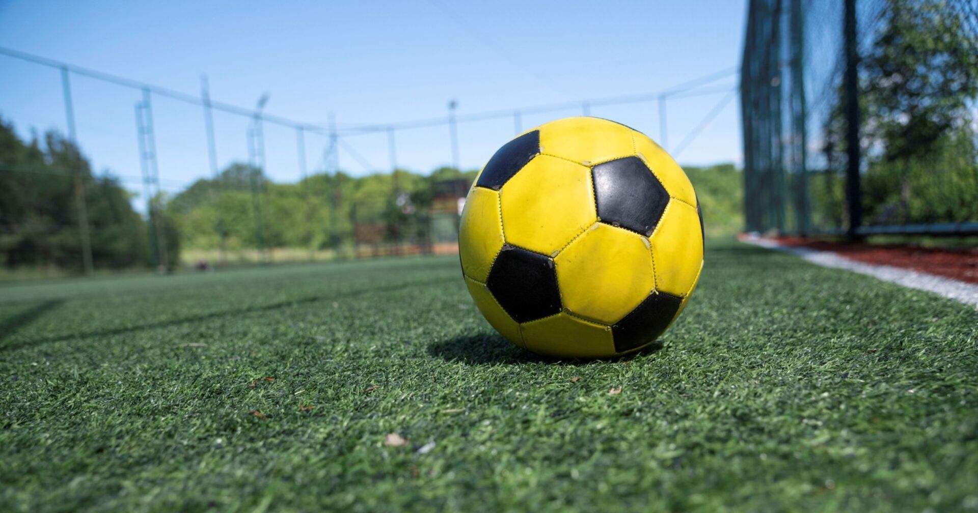 Ein Gelb-Schwarzer Fußball auf einem Trainingsplatz