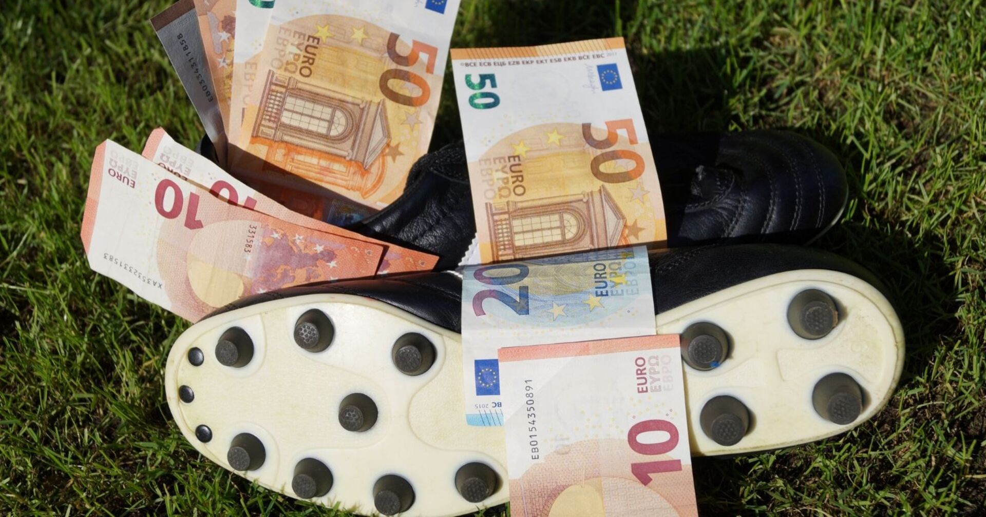 Fußballschuh mit Geldscheinen auf Rasen