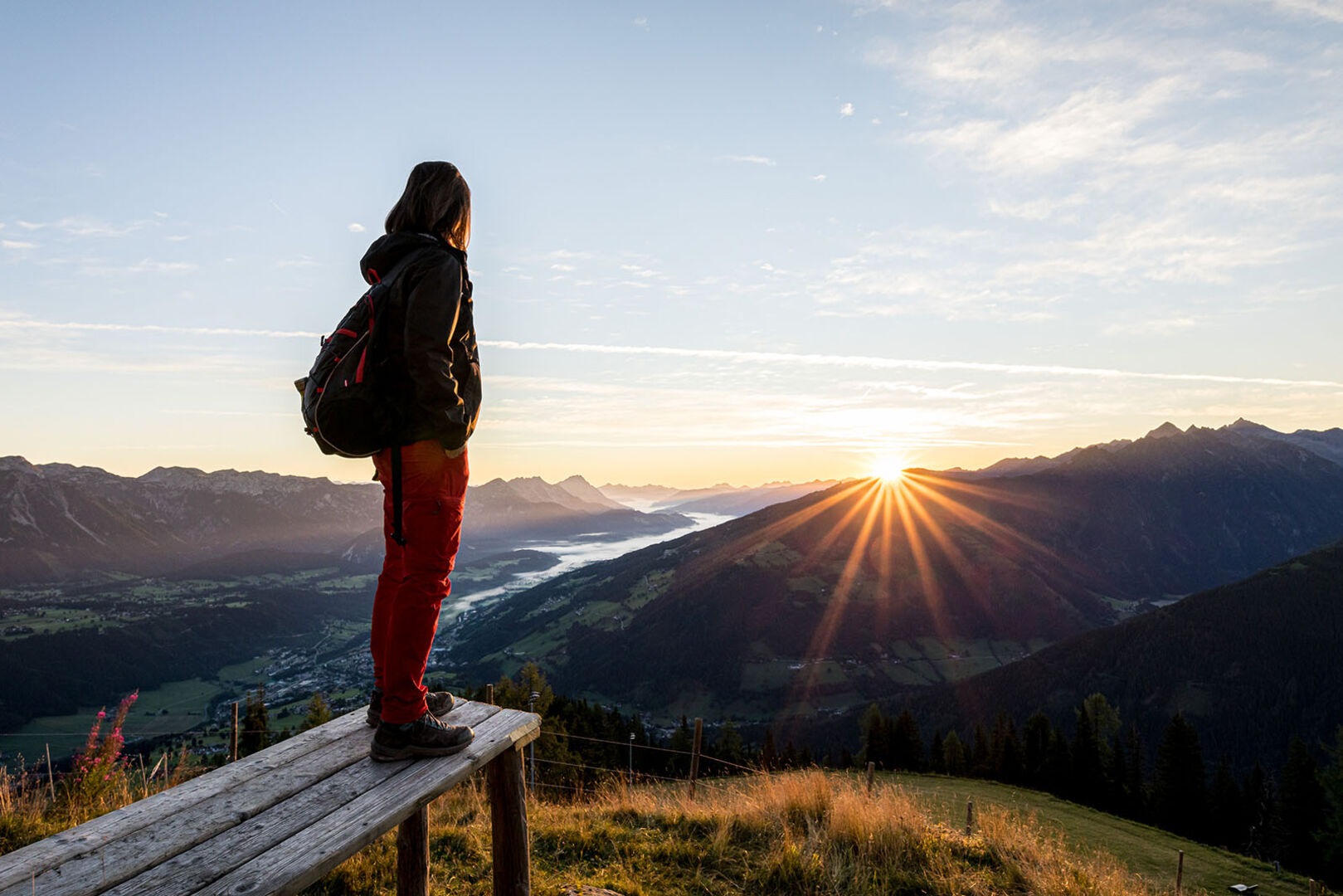 Wanderin blickt in den Sonnenaufgang | Credit: Martin Huber / picturedesk.com