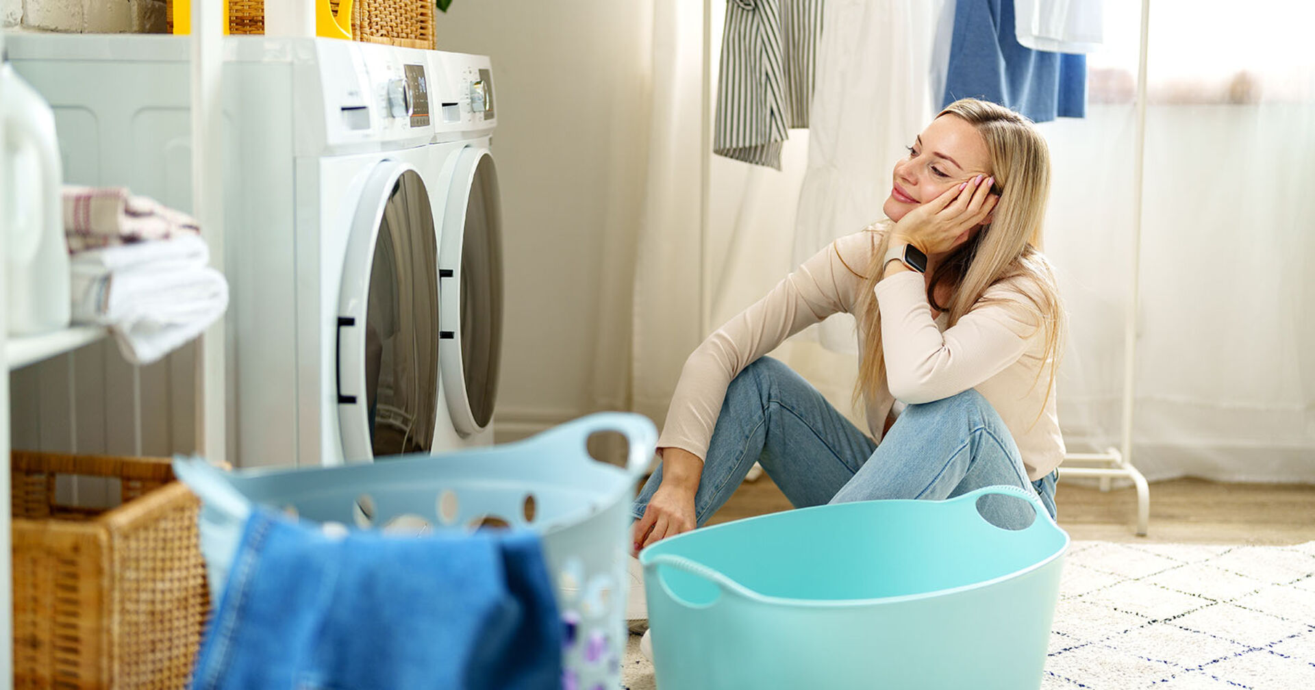 Frau sitzt vor Waschmaschine | Credit: iStock.com/FabrikaCr