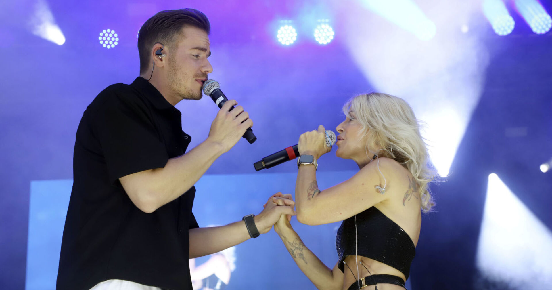 Ein Mann und eine Frau singen und halten sich die Hände auf der Bühne