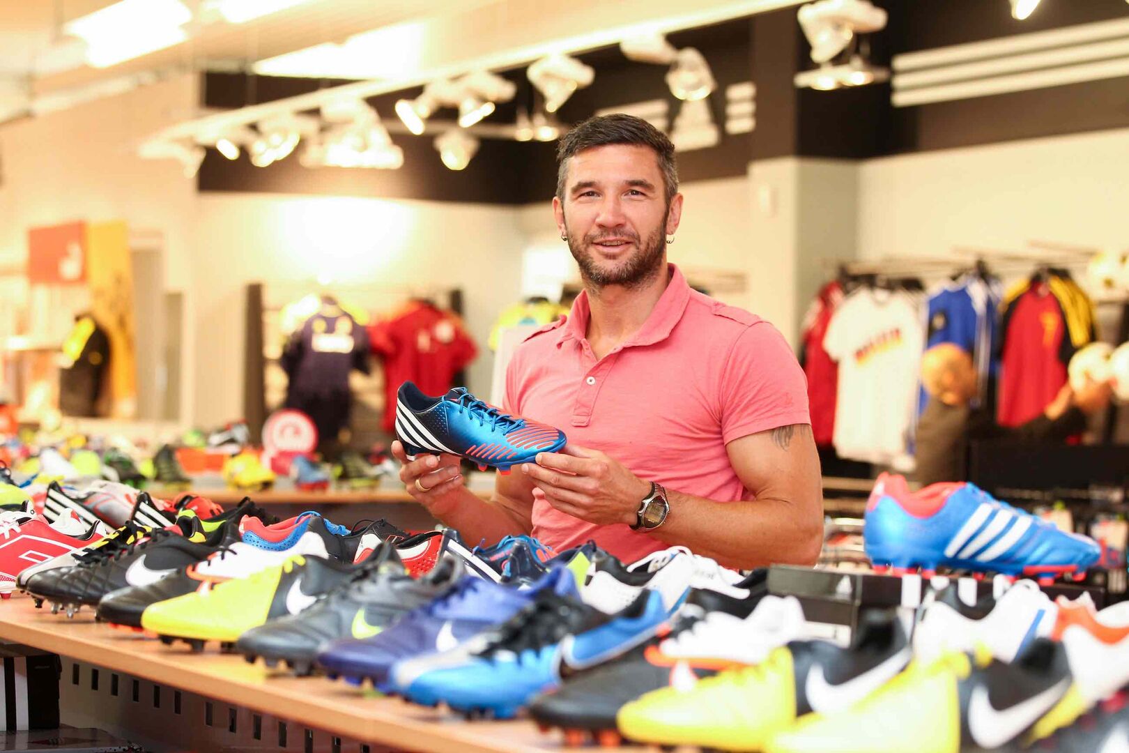 Thomas Winklhofer hält im Sportgeschäft einen Fußballschuh hoch.