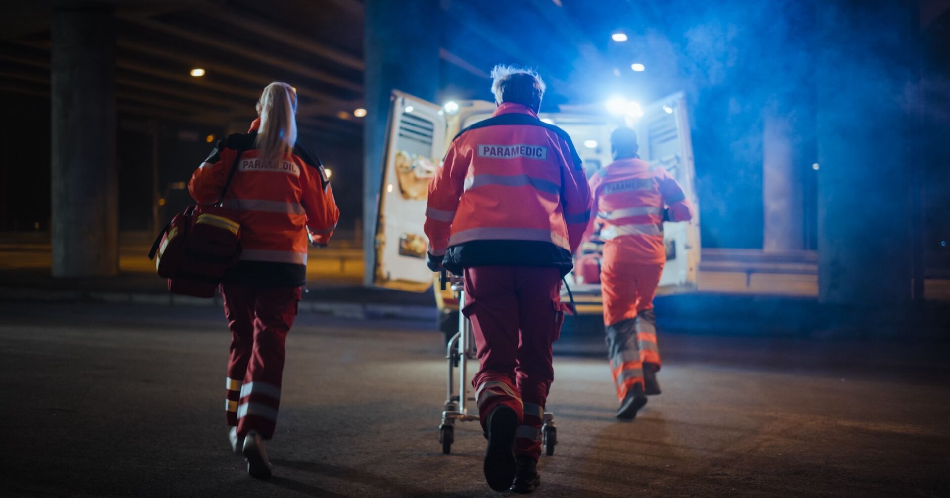 Drei Rettungskräfte eilen zum Notarztwagen.