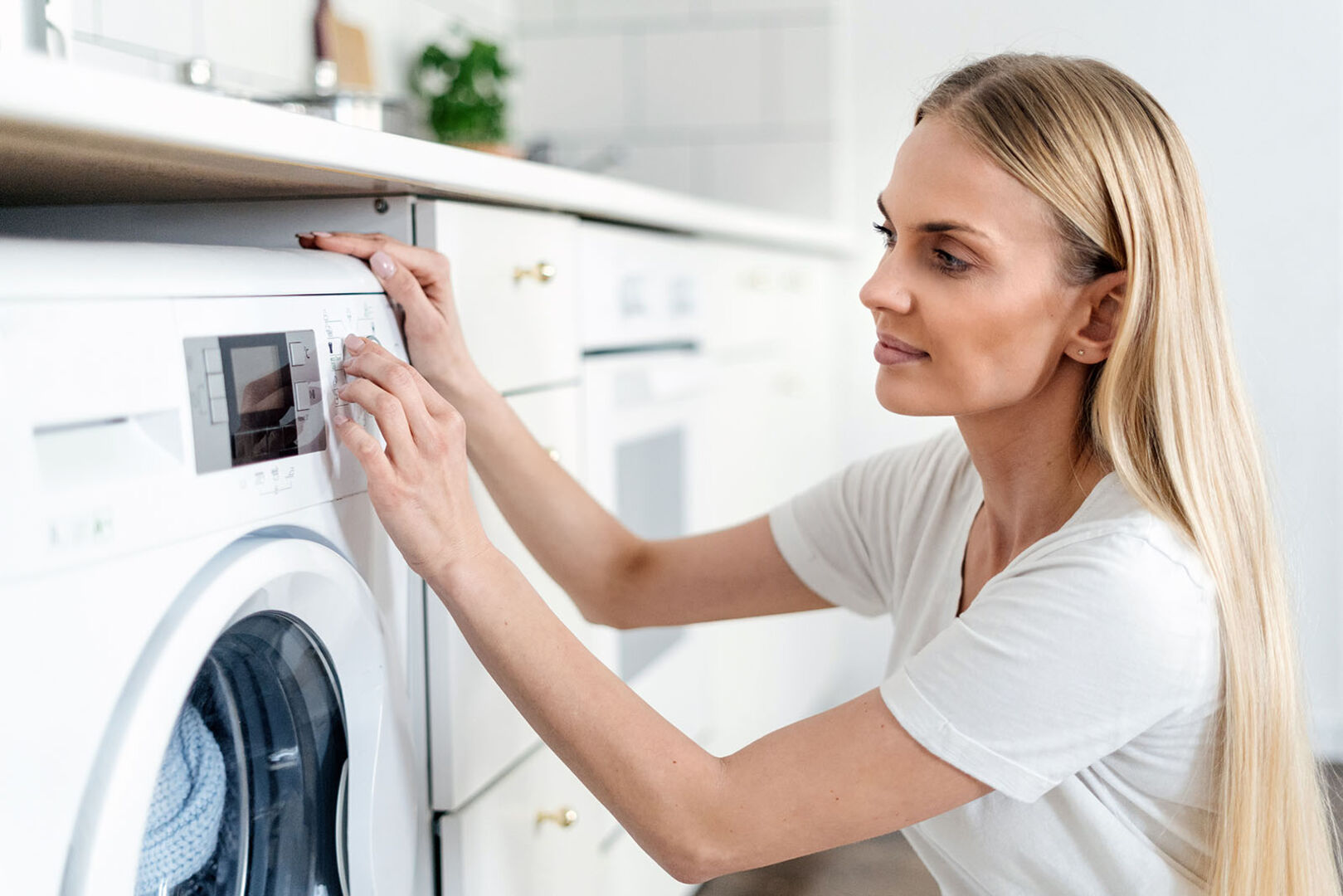 Frau schaltet Waschmaschine ein | Credit: iStock.com/brizmaker