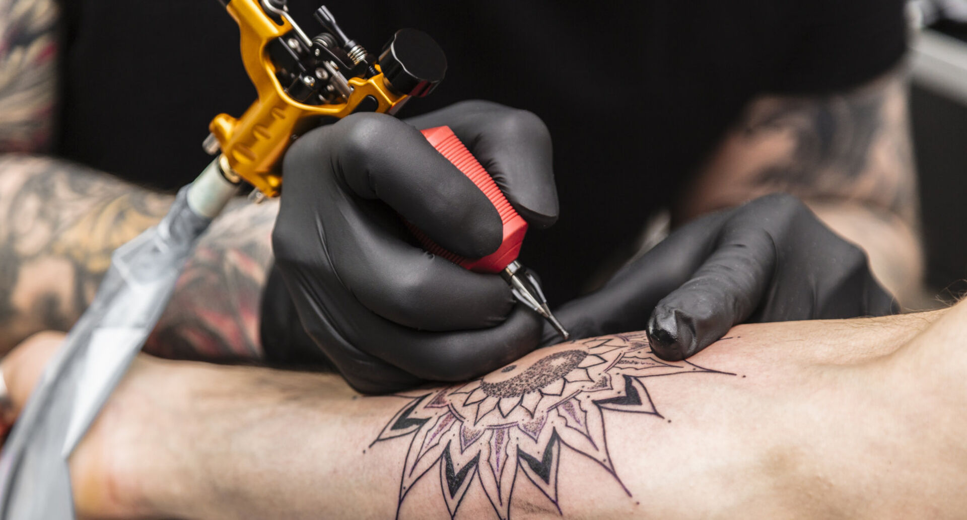 Mann tätowiert einem anderen Mann den Unterarm