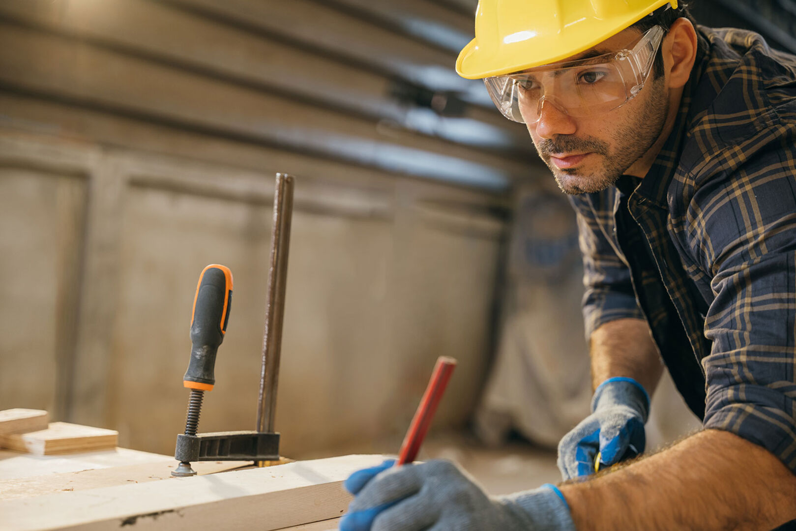 Junger Mann mit Helm beim Zurechtschneiden von Holzplatten | Credit: iStock.com/Sorapop