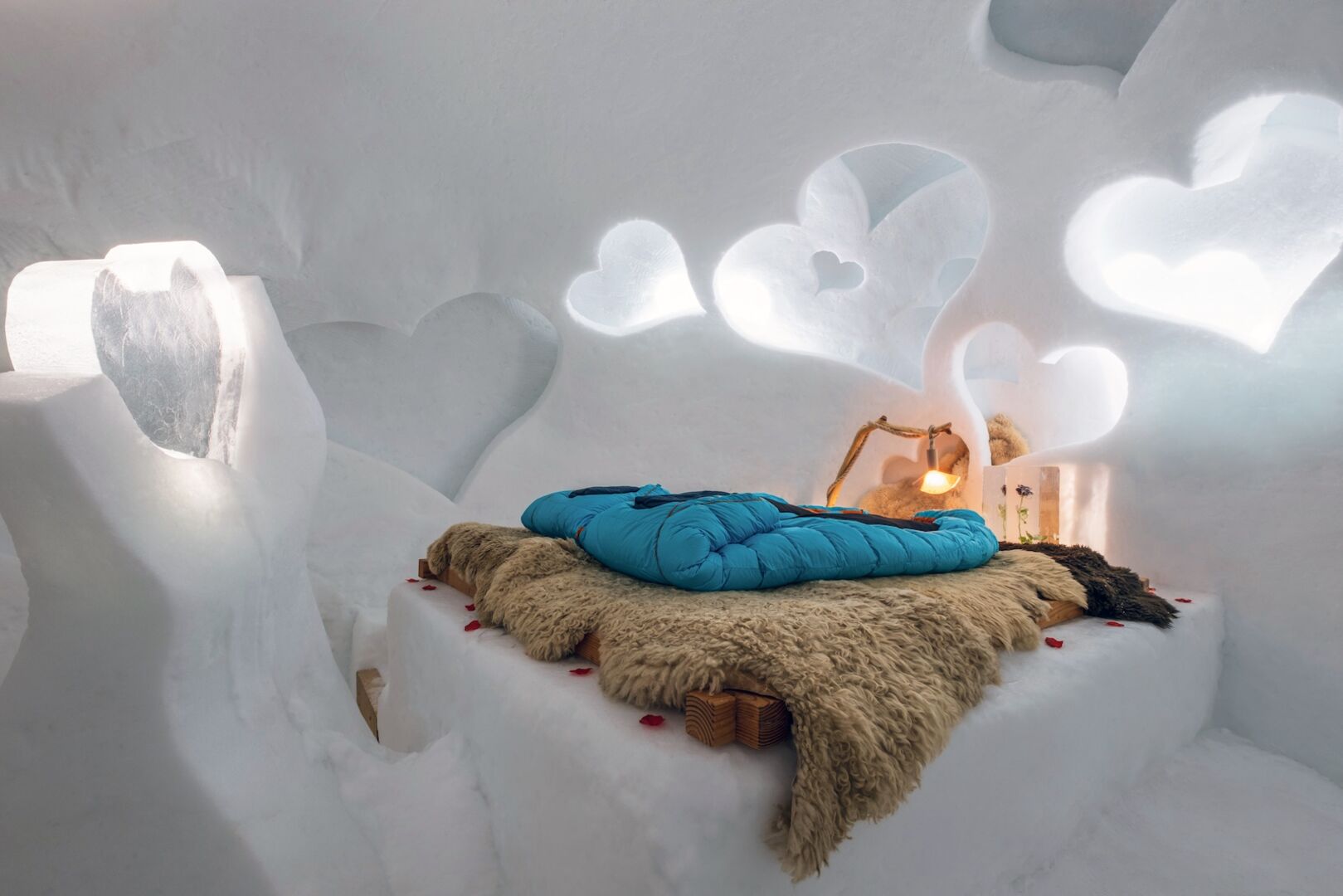 Doppelbett mit Fell und Schlafsack in einem Iglu mit Herzen