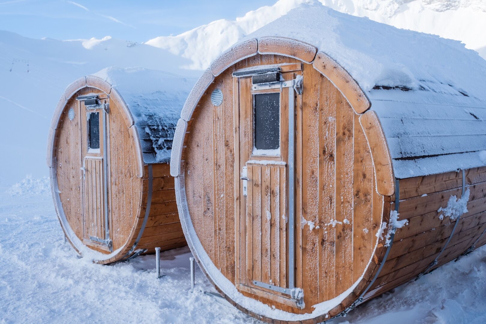 Verschneite große Fässer, in denen sich eine Sauna befindet