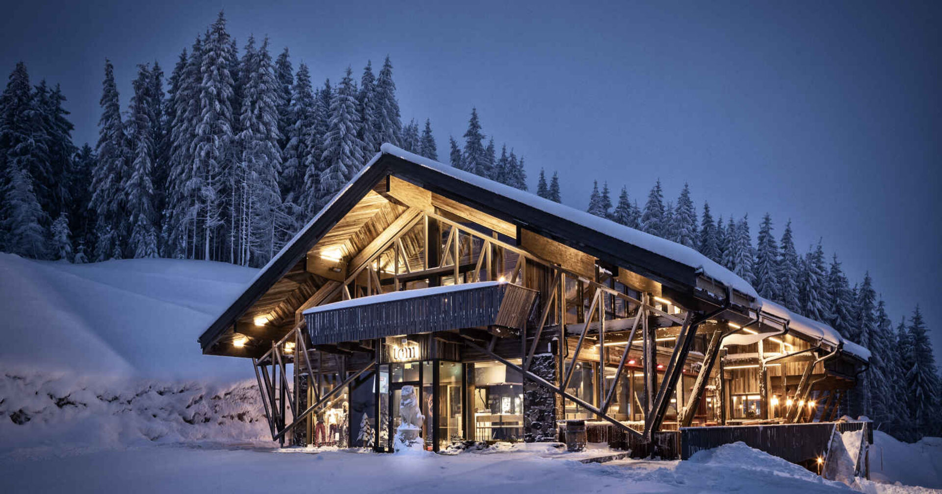 Beleuchtete Almhütte in einer Winterlandschaft.