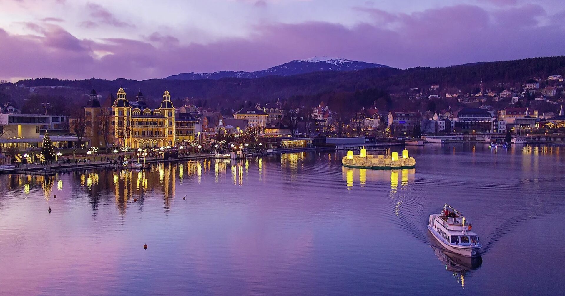 Schwimmender Adventkranz und ein Boot vor Velden