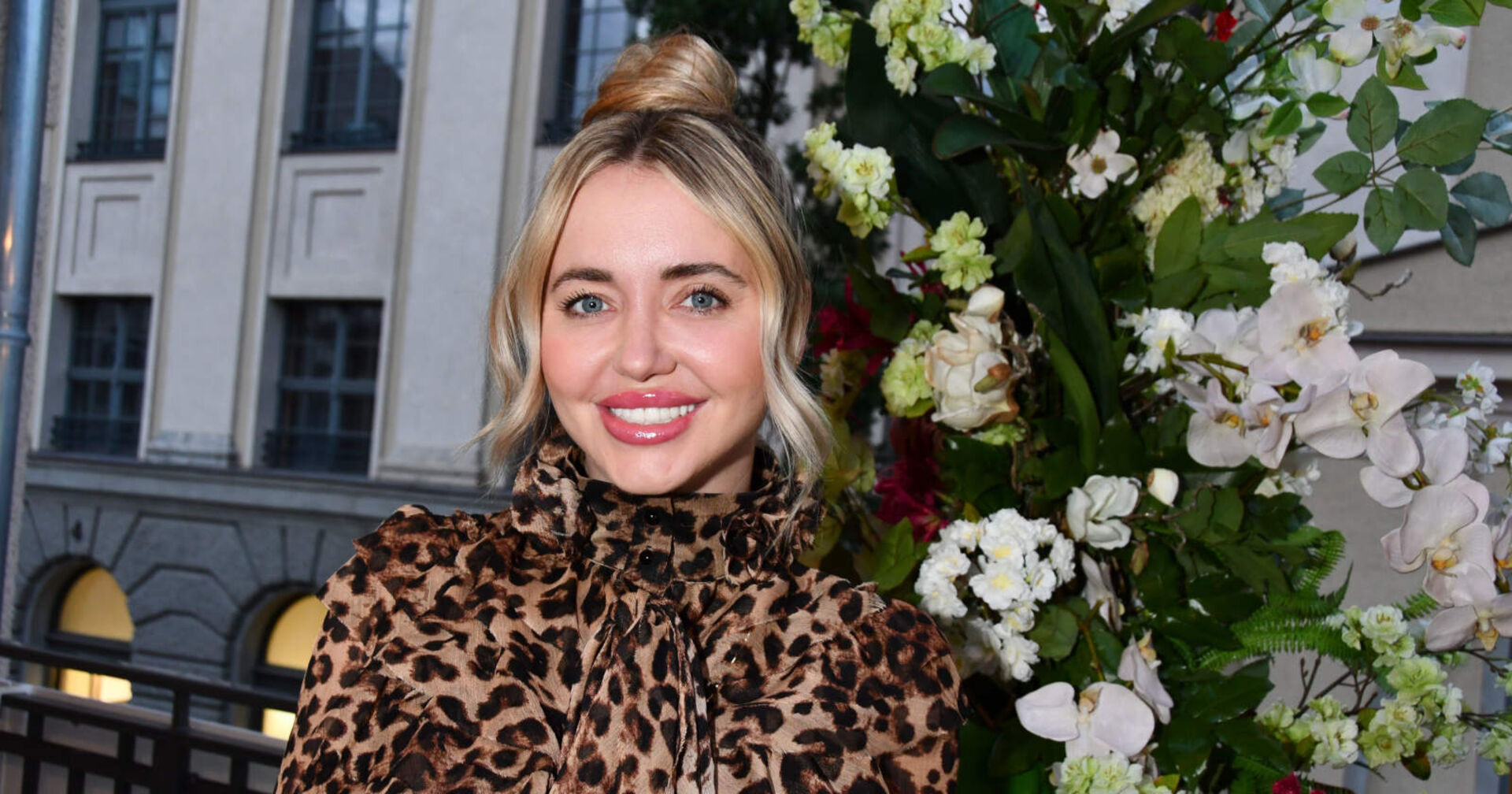 Blonde Frau in einem Leopardenkleid lächelt in die Kamera