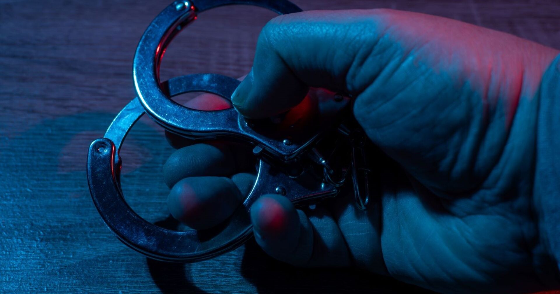 Ein Mann hält Handschellen in der Hand.