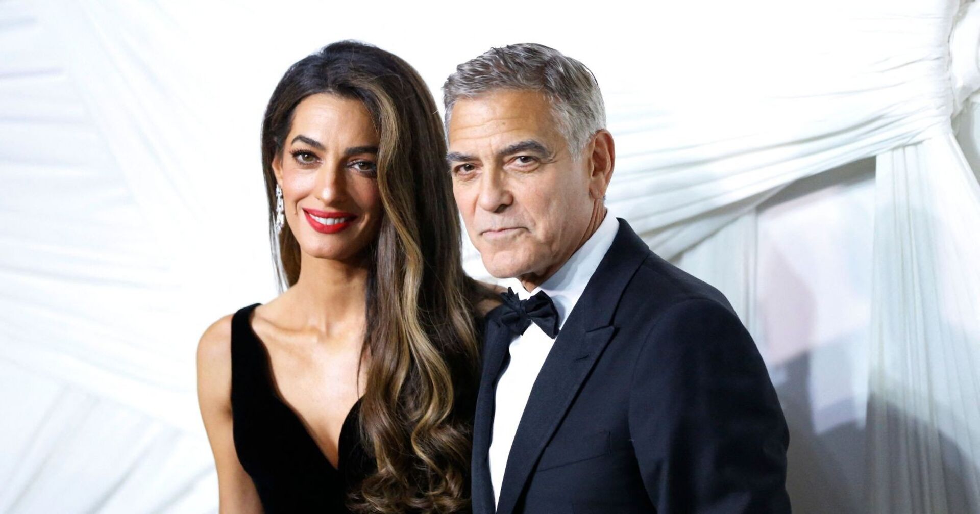 Amal und George Clooney posieren zusammen.