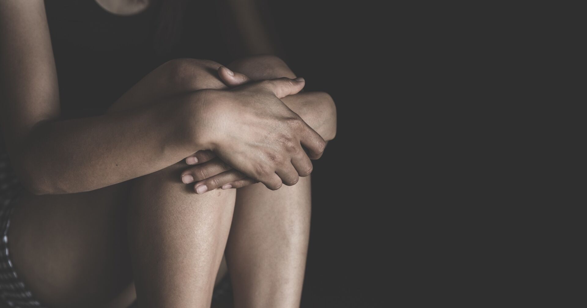 Ein verängstigtes Mädchen sitzt in einem dunklen Raum.