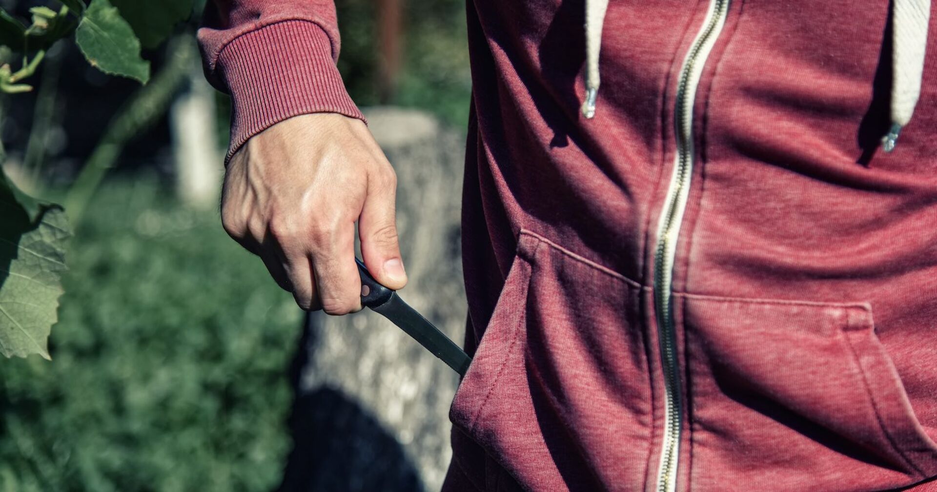 Ein Mann zückt aus seiner roten Jacke eine Messe.