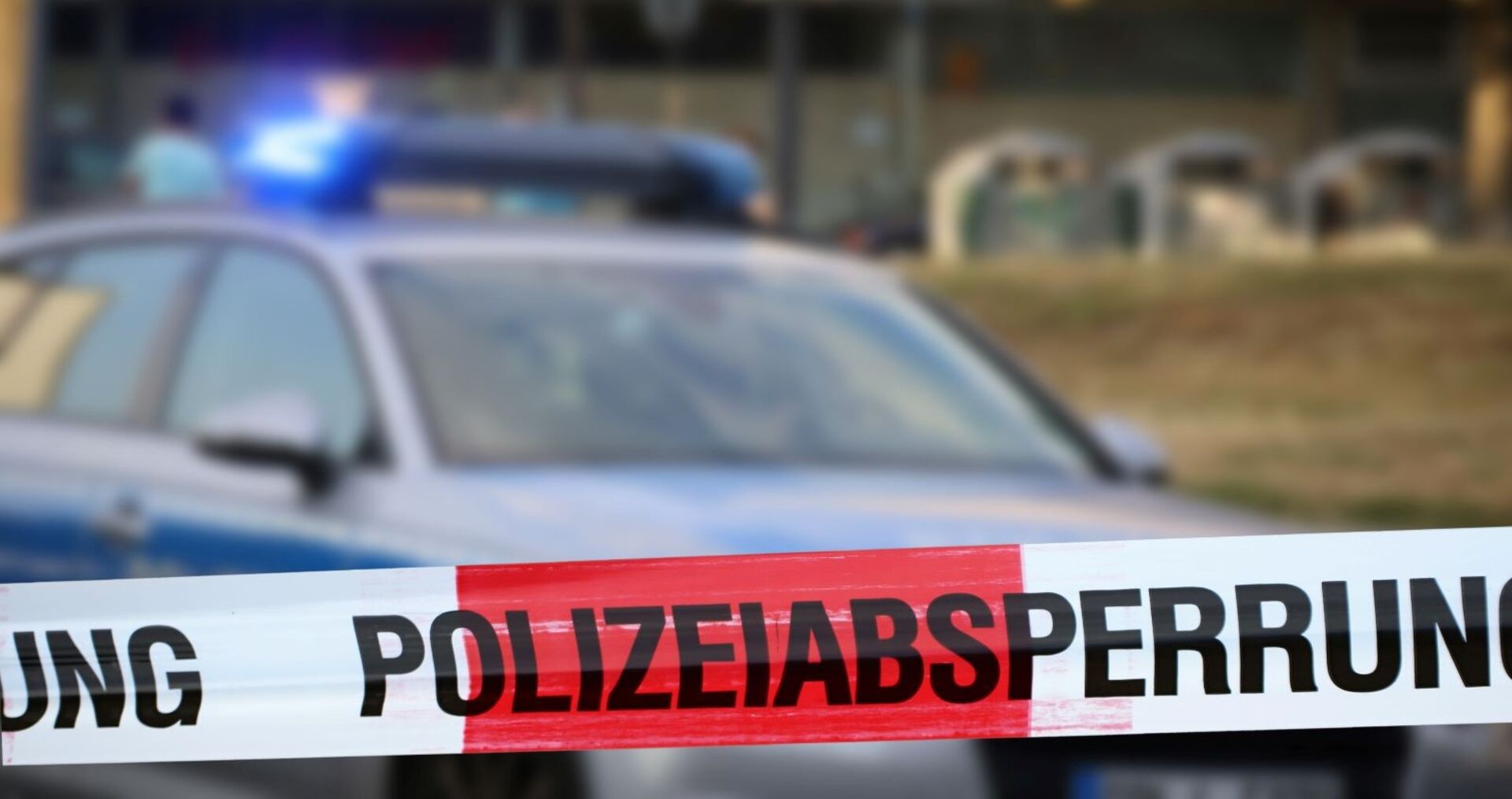 Ein Polizeiauto und eine Absperrung davor.