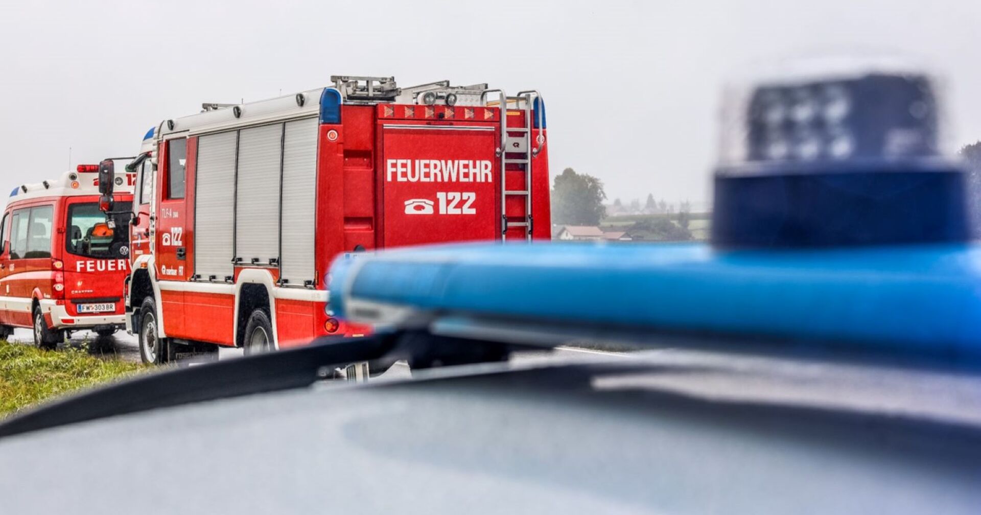 Zwei Feuerwehrautos und ein Polizeiwagen an einen Unfallort.