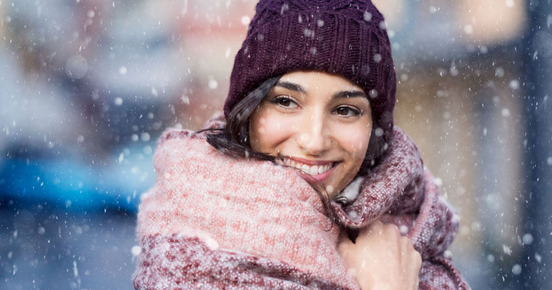 Frau steht lächelnd im Schneeschauer | Credit: iStock.com/Ridofranz