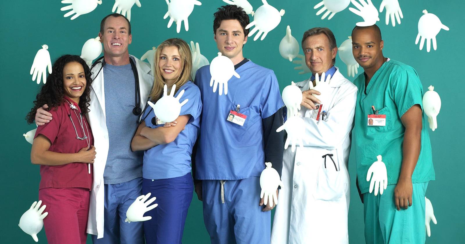 Die Hauptdarsteller der Fernsehserie Scrubs, die in Krankenhausbekleidung vor einem türkisen Hintergrund stehen, während aufgeblasene weiße Einweghandschuhe durch die Luft fliegen