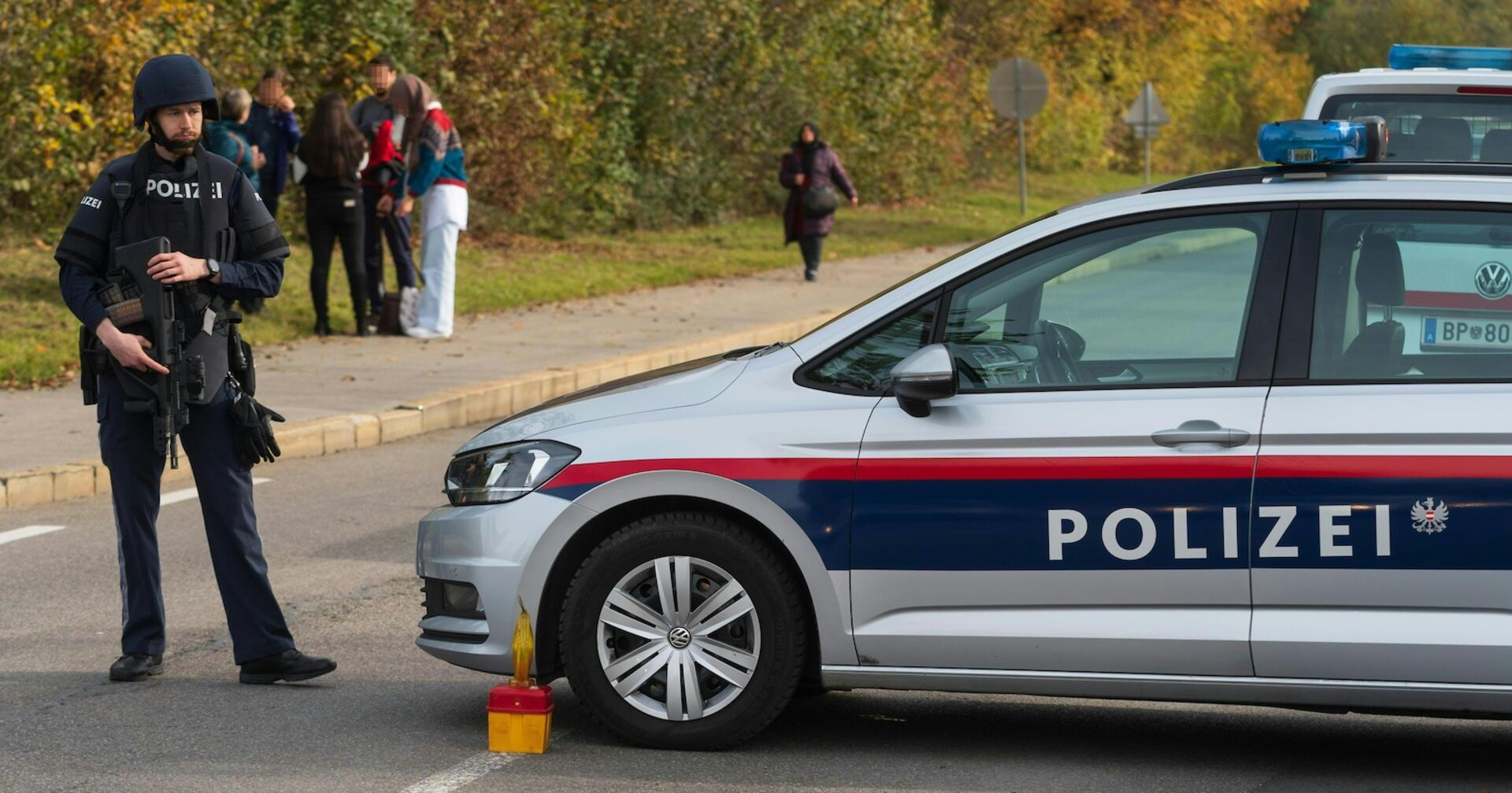 Ein Polizist im Einsatz, neben ihm ein Polizeiauto.