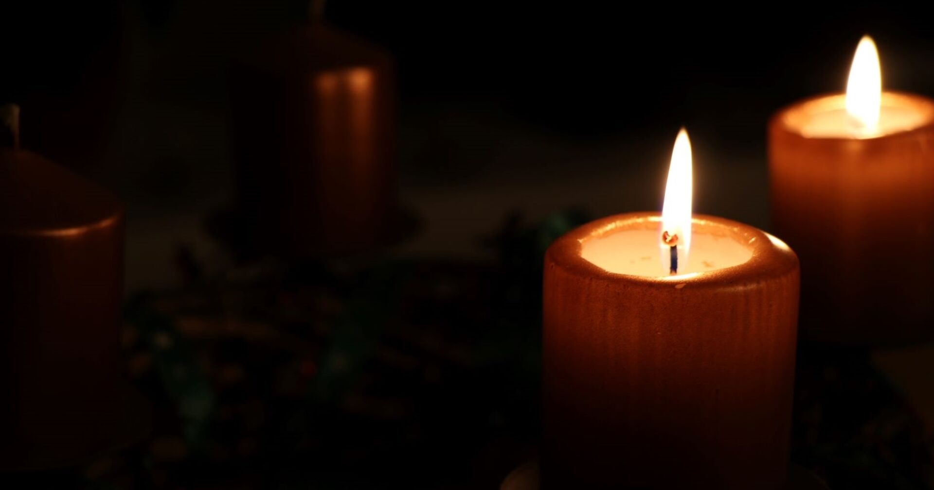 Zwei brennende Kerzen in der Dunkelheit.