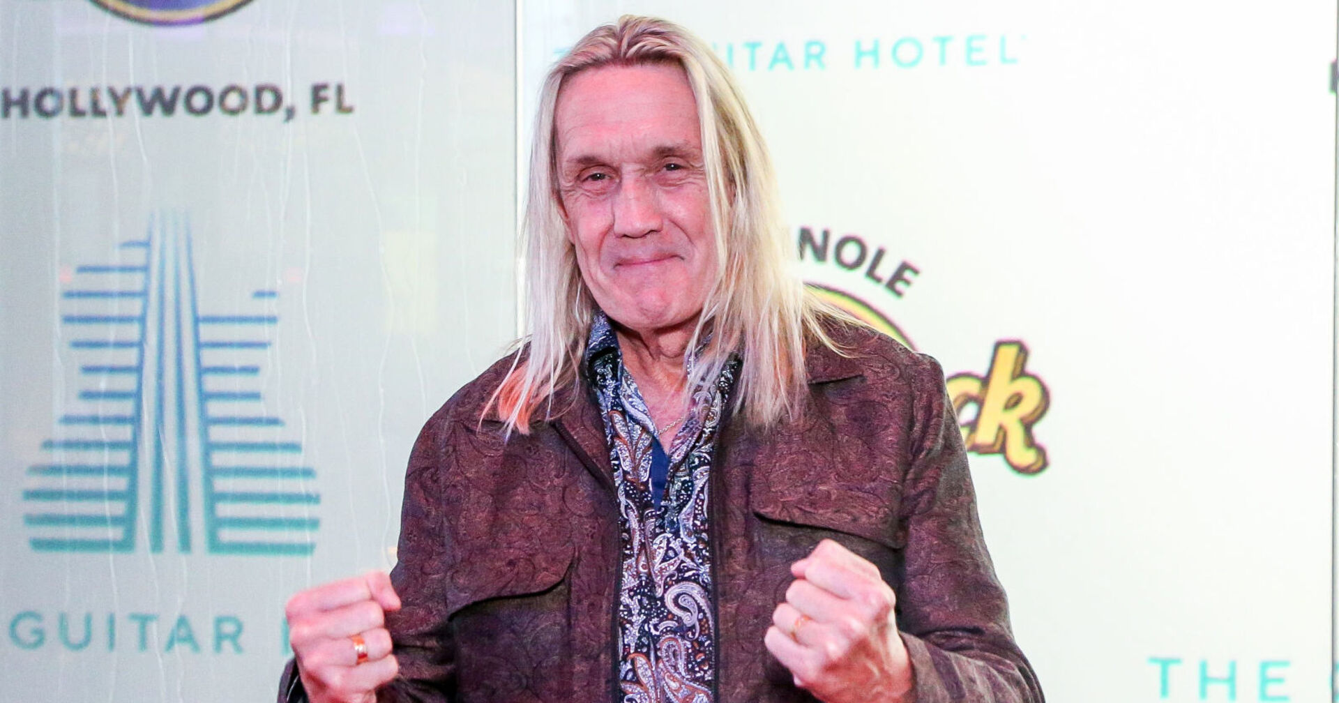 Blonder Mann mit langen Haaren zeigt Fäuste