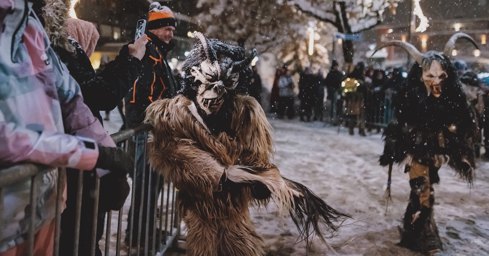 Zuschauer und zwei Krampusse bei einem Lauf.