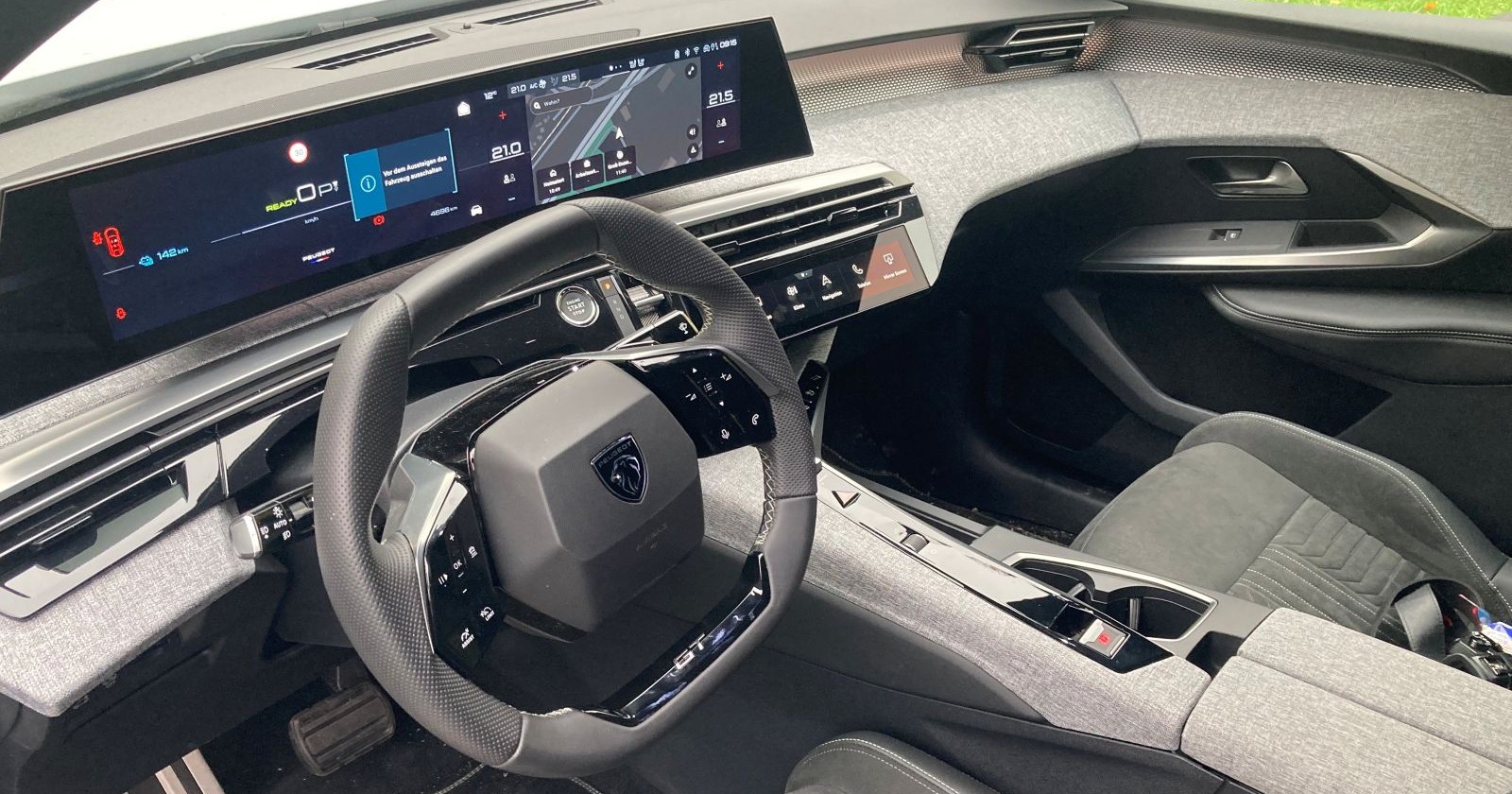 Das Innenleben des Peugeot E-3008: Graue Stoffbezüge, ein helles Lenkrad und das Display geben dem Auto ein sportliches Aussehen.