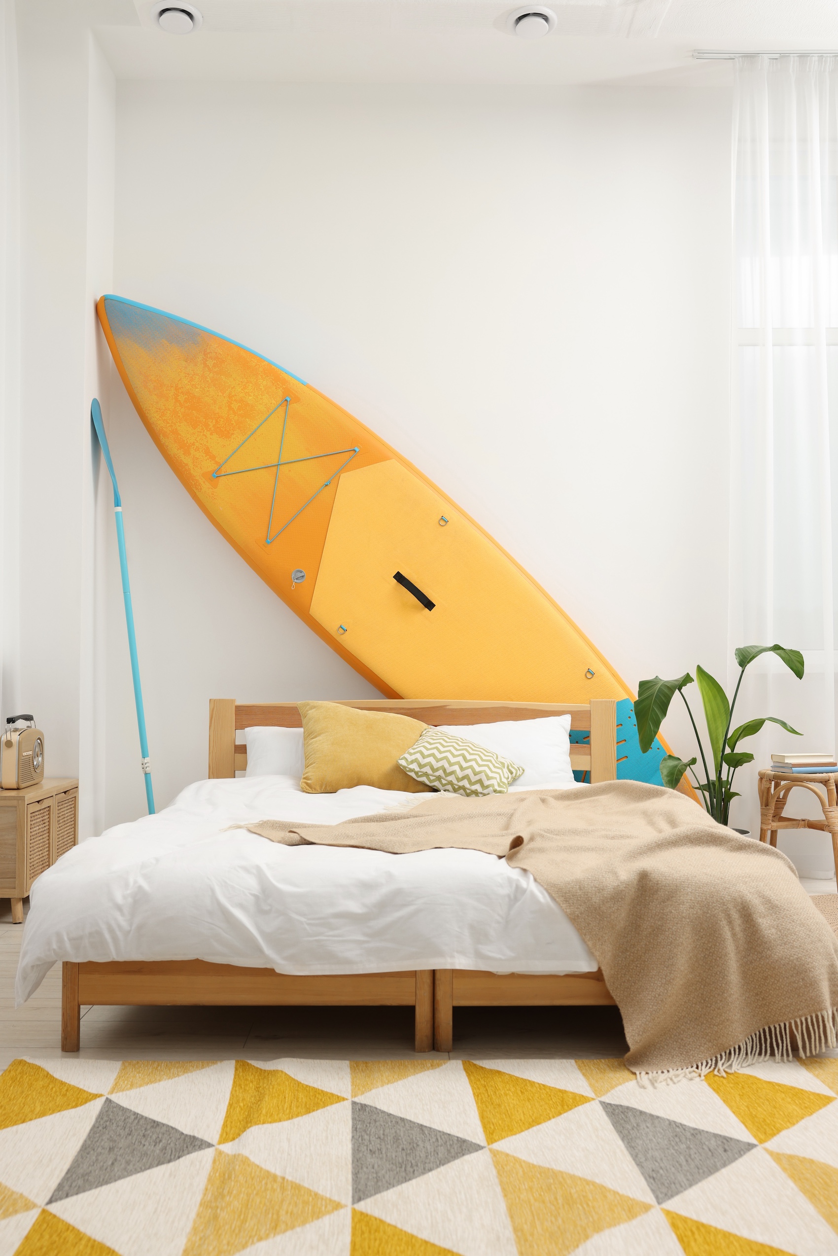 helles Schlafzimmer mit Surfbrett an der Wand