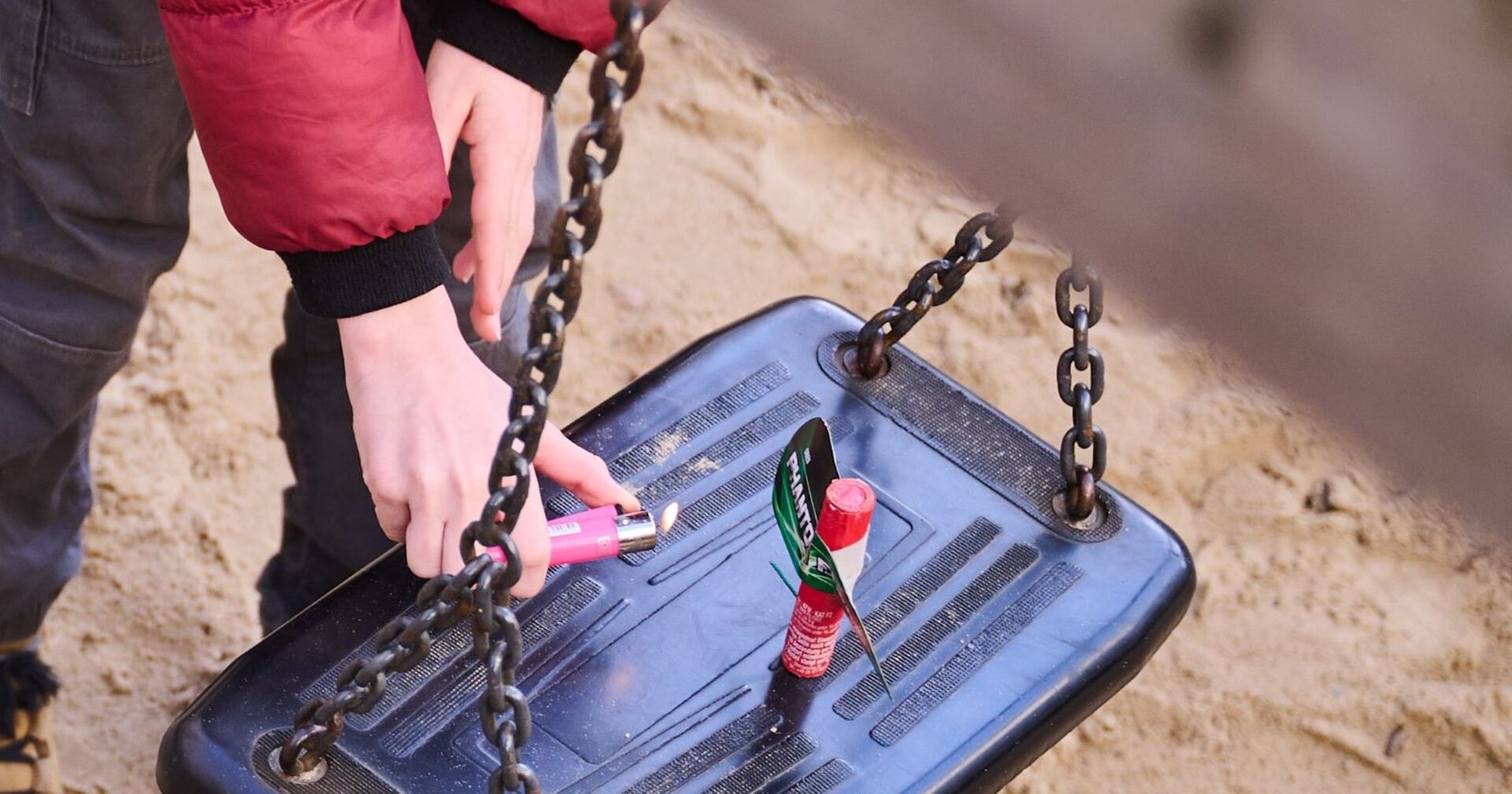 Ein Jugendlicher zündet auf einer Schaukel einen Böller.