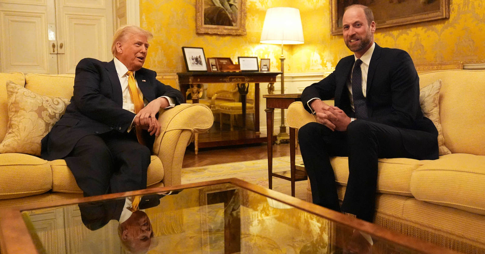 Zwei Männer sitzen in einem hellen Raum auf einem Sofa gegenüber