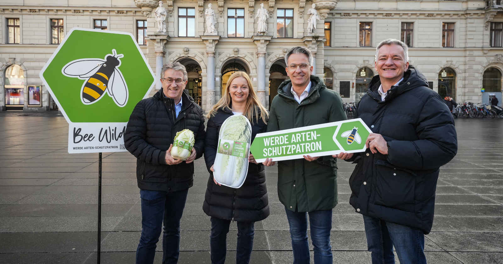Mehrere Menschen mit Tafeln in der Hand stehen vor einem Rathaus