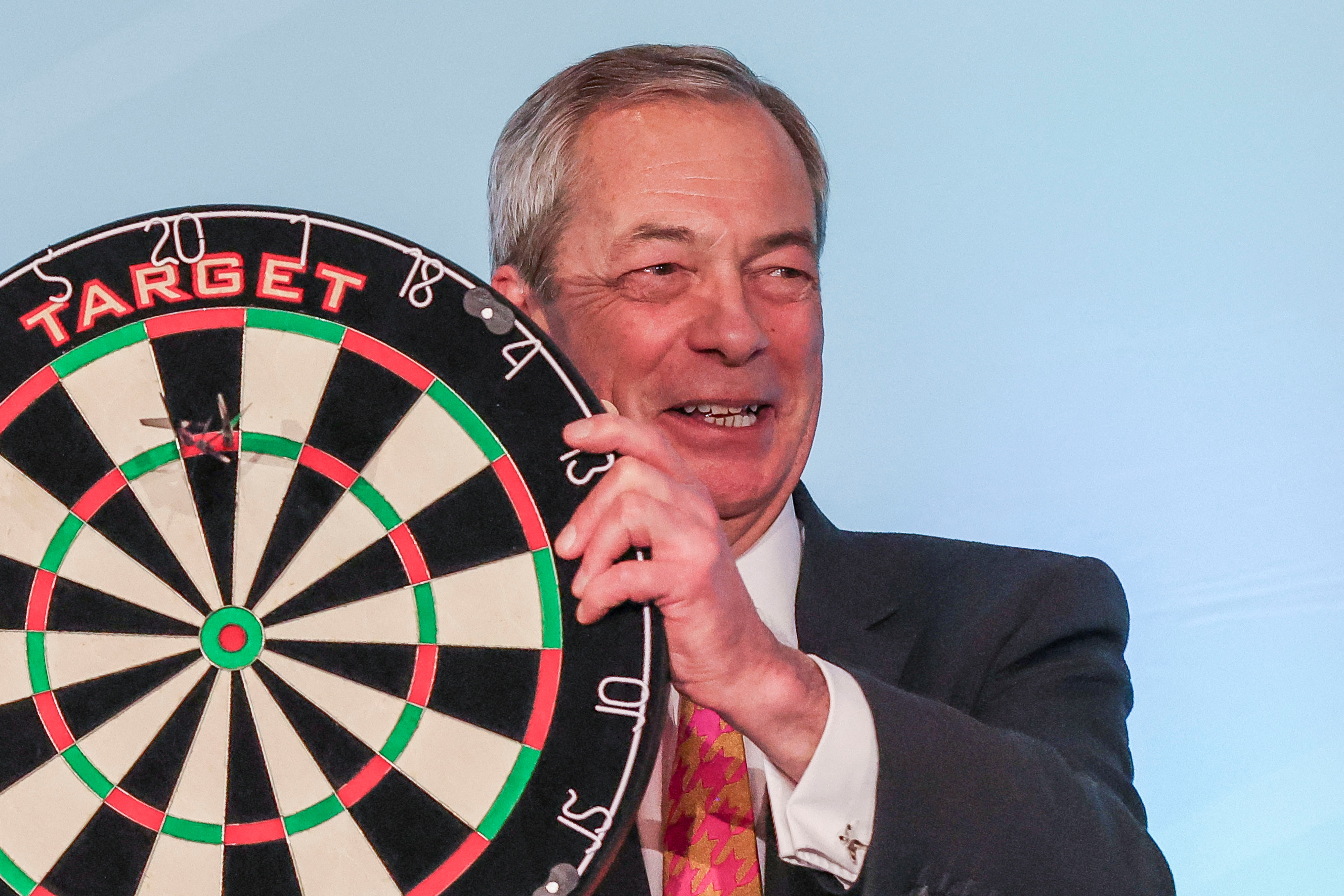Nigel Farage, der eine Dartscheibe in Händen hält