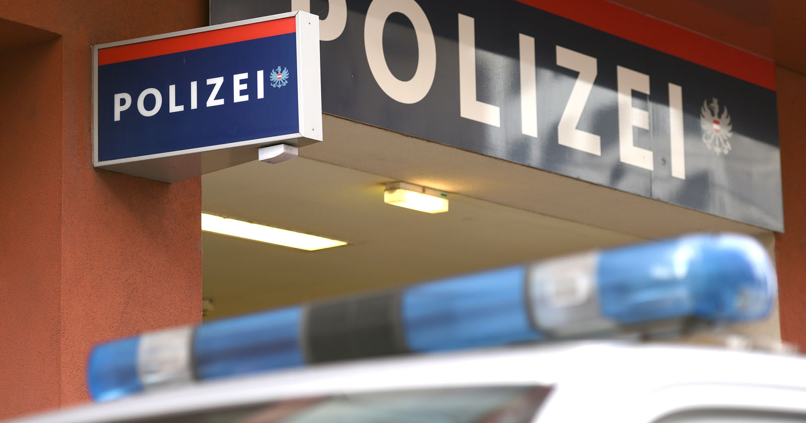 Blaulichtanlage eines Polizeiautos vor einem Gebäude mit einem Schild auf dem das Wort „Polizei“ steht.