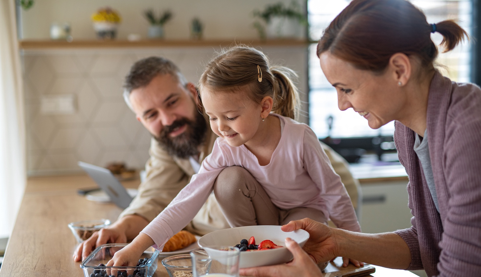 Vater, Mutter und Kind machen gemeinsam Frühstück in der Küche