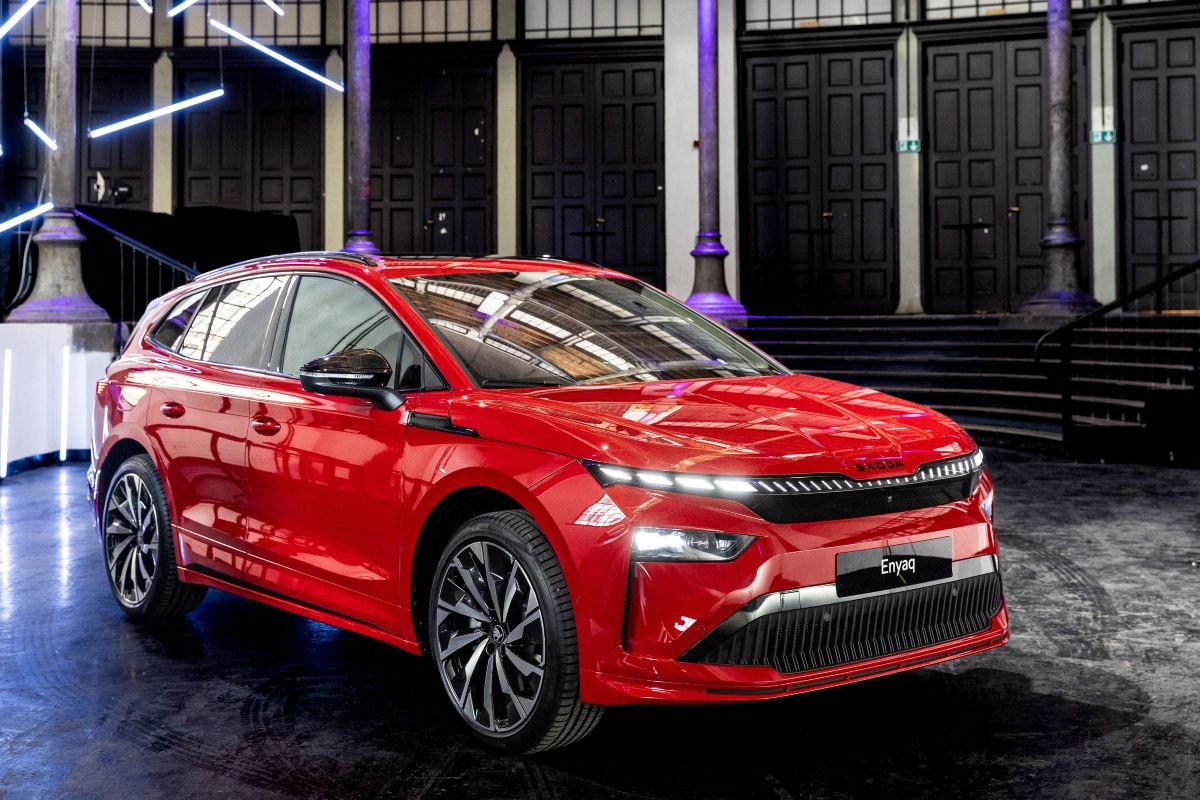 Ein roter Skoda Enyaq steht in einer Halle mit vielen Säulen. Das Auto leuchtet im Licht der Lampen. Die Scheinwerfer des Autos sind eingeschaltet.