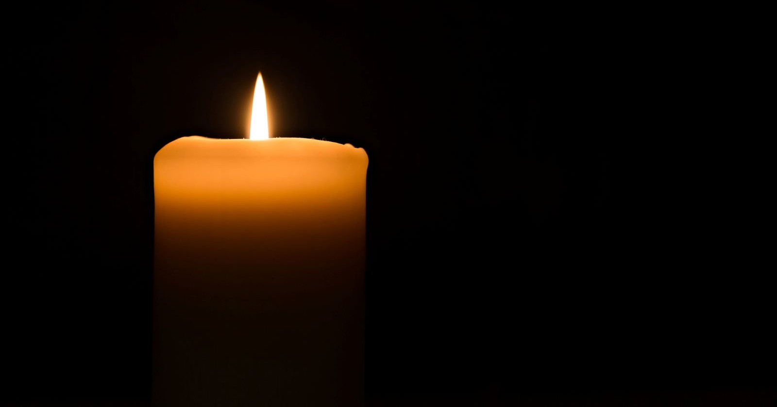 Totenkerze vor schwarzem Hintergrund