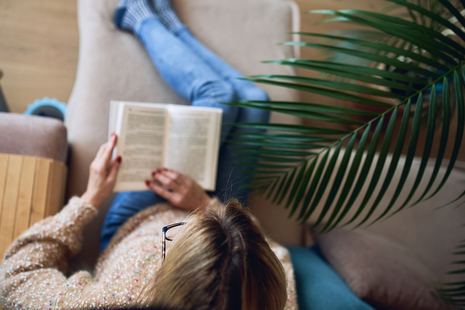 Frau liest auf der Couch ein Buch | Credit: iStock.com/Geanna8