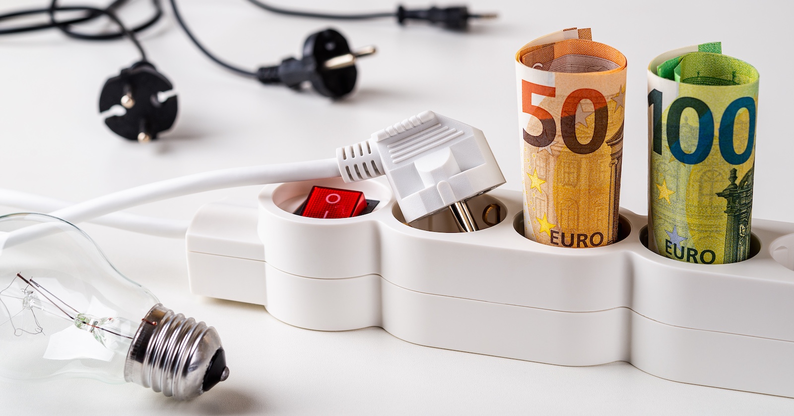 Strom-Kippschalter und Euro-Scheine in den Steckdosen.