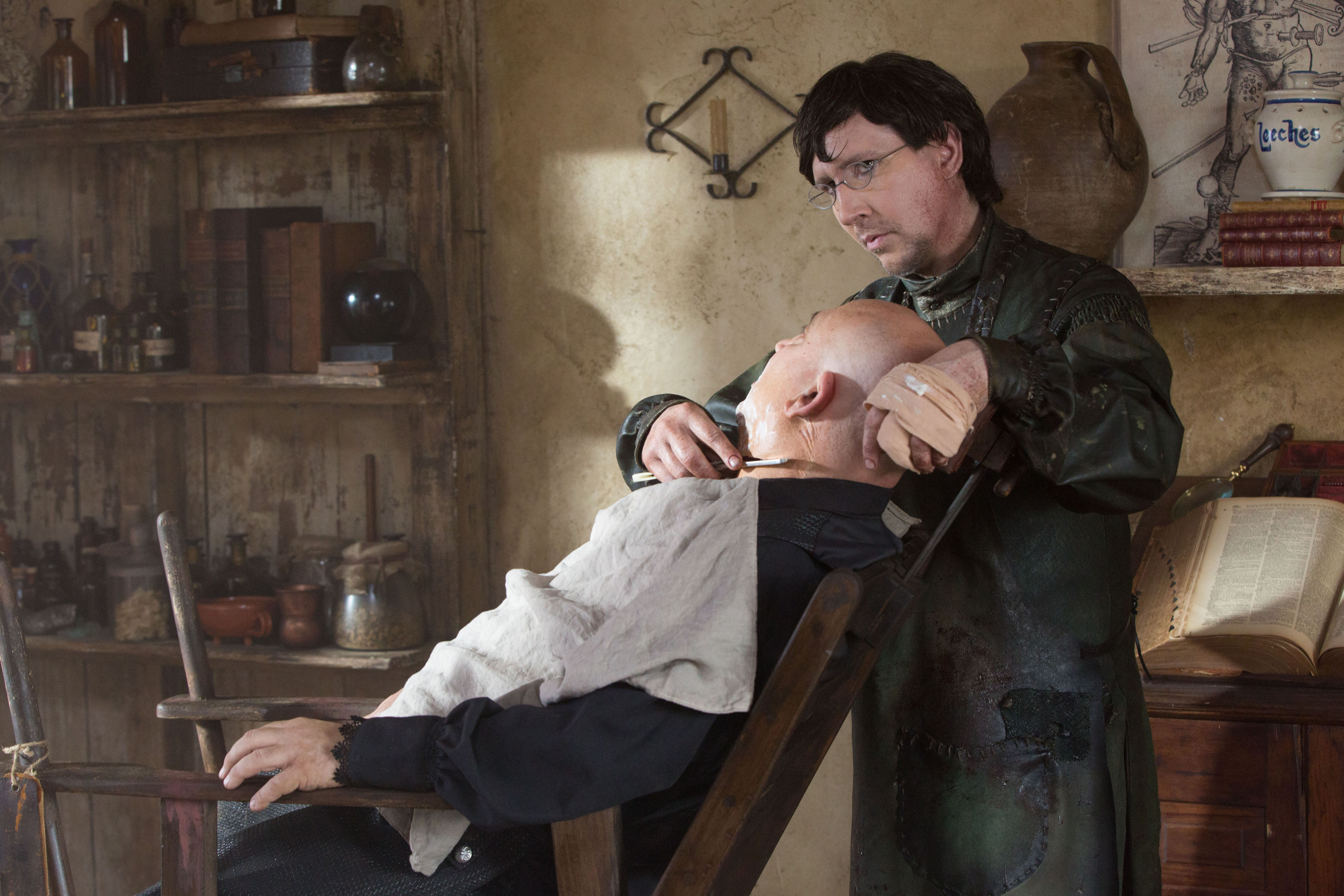 Szene aus der Serie &quot;Salem&quot; in der der von Marilyn Manson verkörperte Charakter einem in einem Stuhl sitzenden Mann ein Rasiermesser an den Hals hält