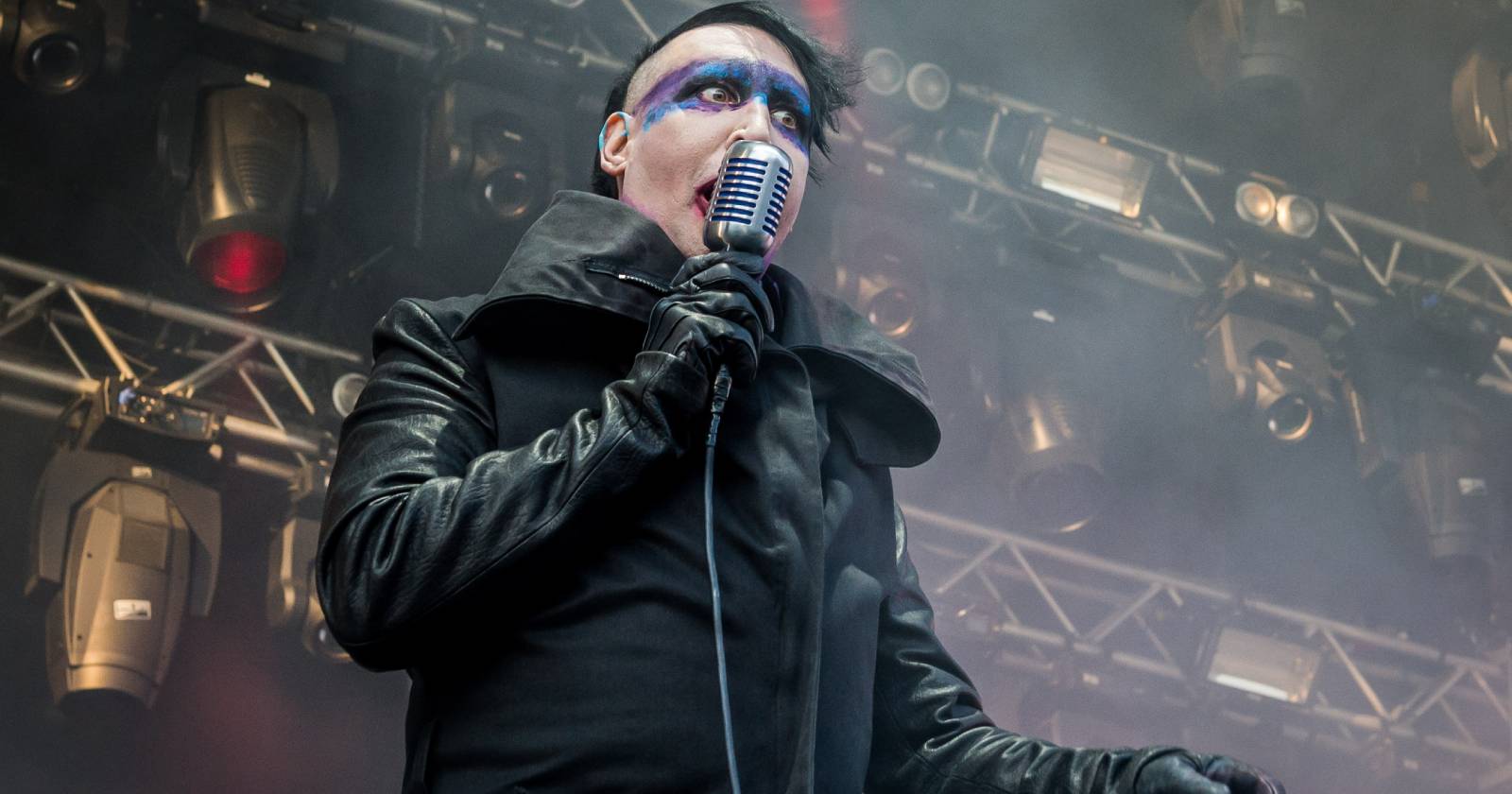 Marilyn Manson während eines Live-Auftritts, bei dem er einen langen schwarzen Mantel und blau-weißes Make-up trägt