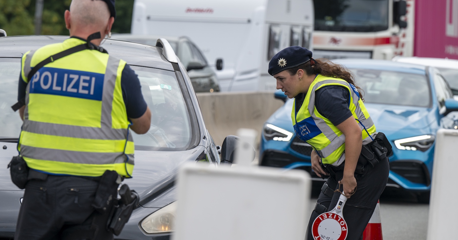 Zwei Polizisten kontrollieren ein Auto.