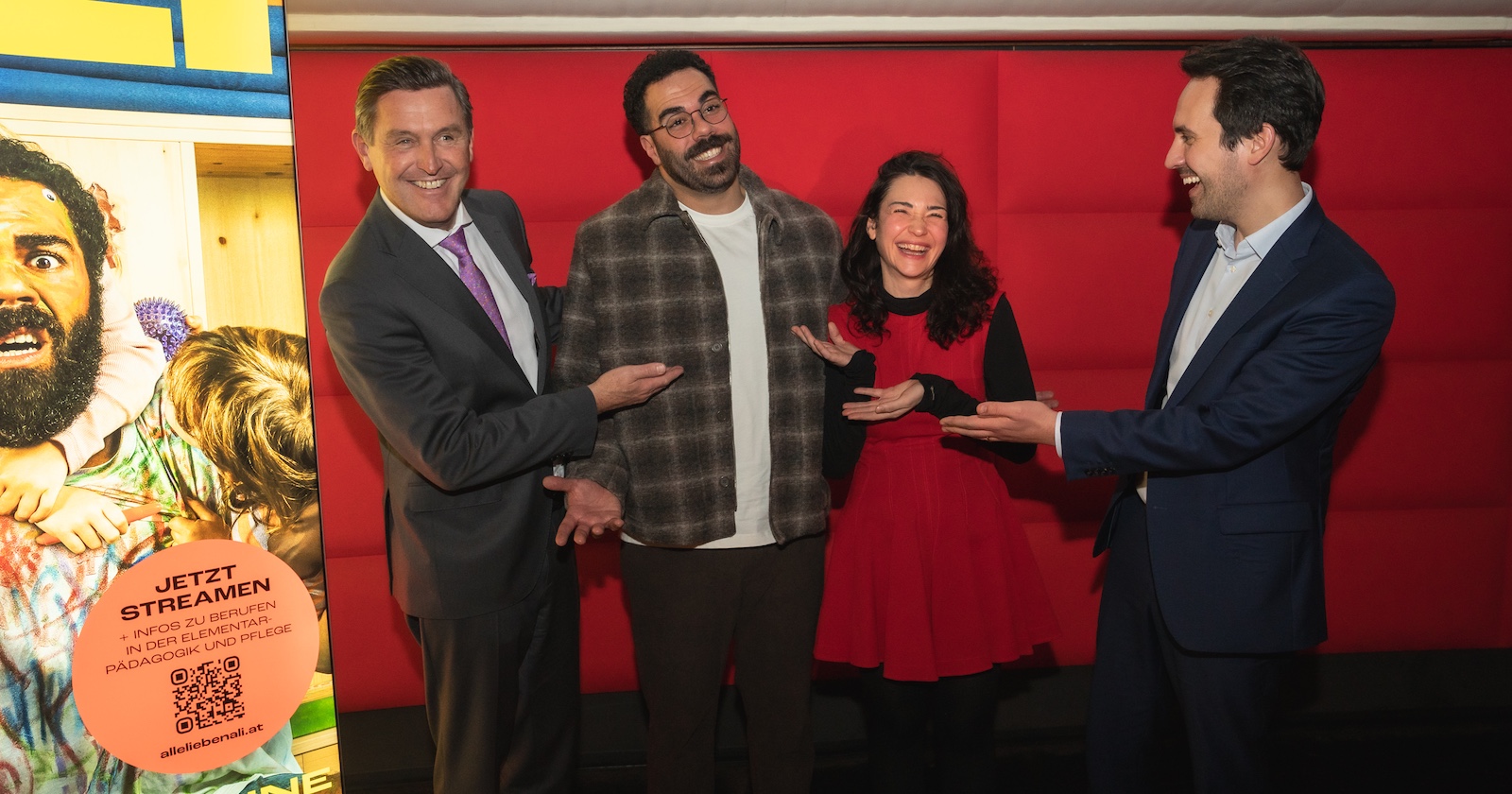 Vier Personen scherzen vor einem roten Kino-Vorhang