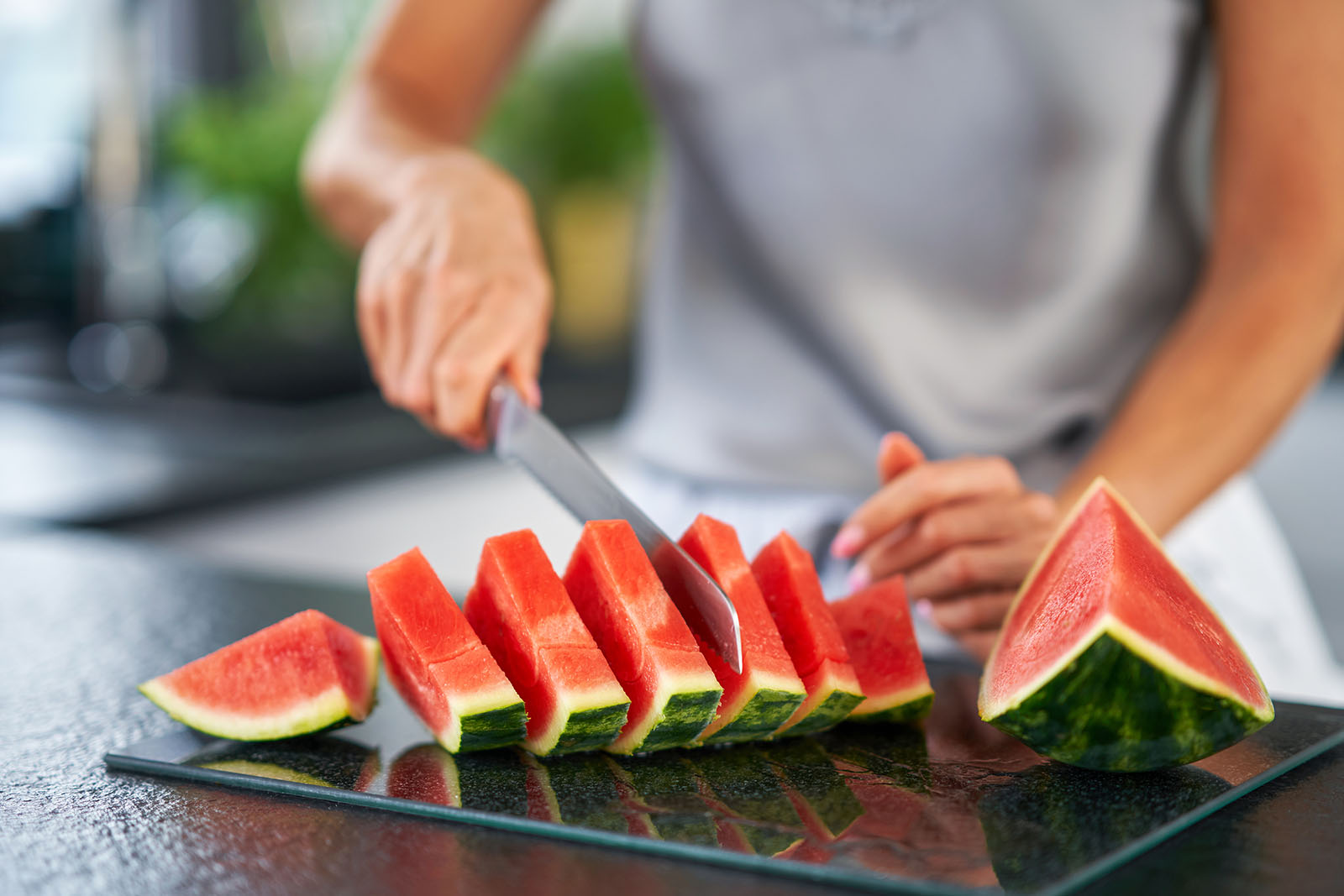 Frau schneidet Wassermelone klein | Credit: iStock.com/macniak