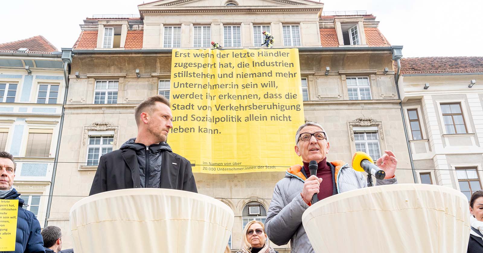 Zwei Männer stehen vor einem großen gelben Plakat