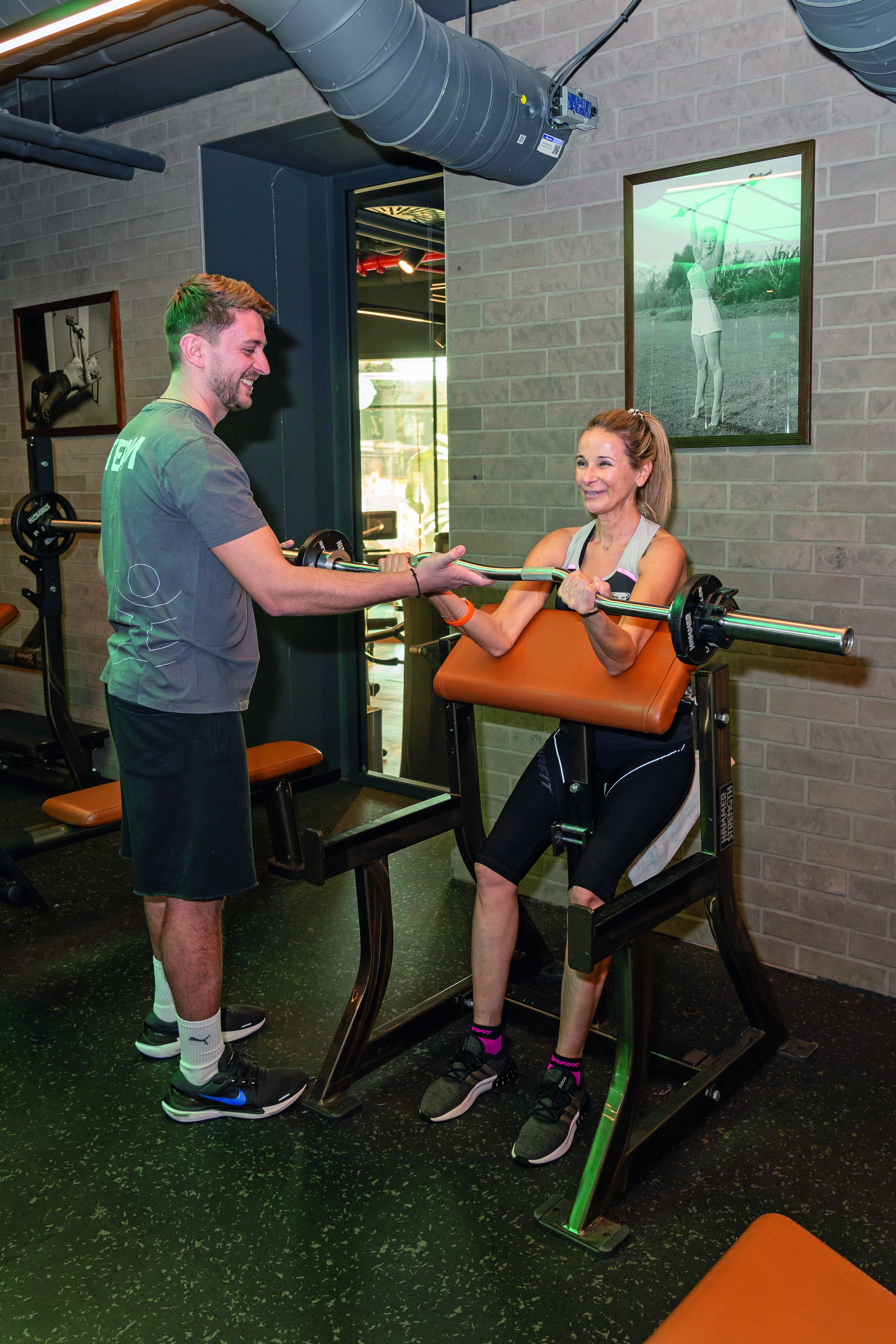 Frau trainiert gemeinsam mit einem Trainer im Gym